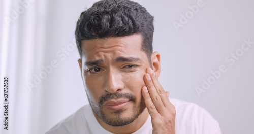 A young man worried about the wrinkles on his face while standing in front of mirror in bathroom at home.
