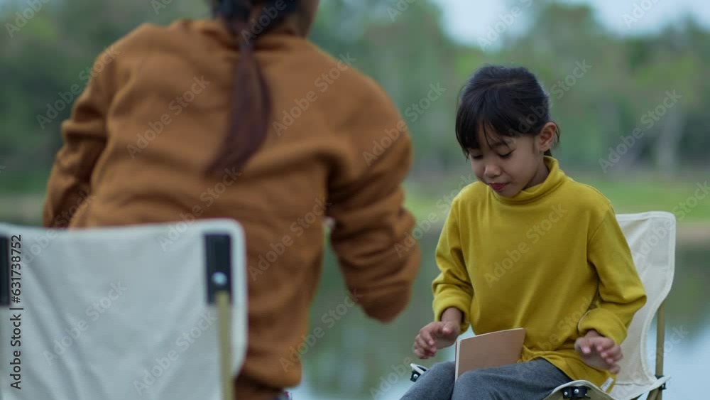 The Mother feeding snacks to daughter at camp, and happy to eat. The Mother feeding snacks to daughter at camp, and happy to eat.