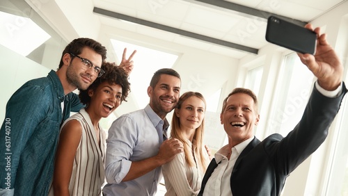Happy moments. Group of smiling colleagues taking selfie and gesturing while standing in the modern office