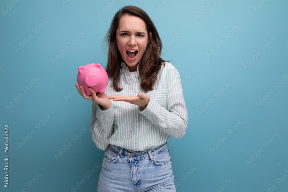 smiling attractive european brunette young lady keeps money in a pink piggy bank