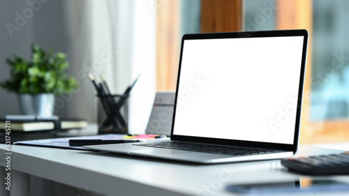 Home office interior , laptop computer with blank screen and office supplies on white table.