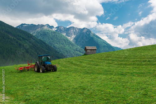 Small tractor cutting grass on alpine field