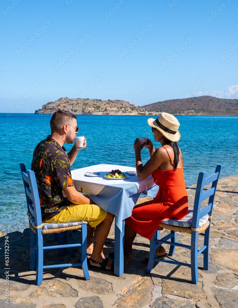 Crete Greece Plaka Lassithi, a traditional blue table and chairs on the beach in Crete Greece. Paralia Plakas, Plaka village Crete. a couple drinking coffee a t waterfront during vacation in Greece