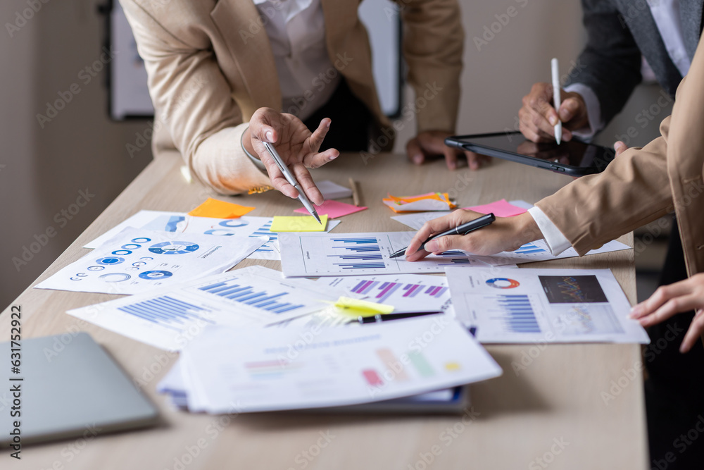 Group of confident business people point to graphs and charts to analyze market data, balance sheet, account, net profit to plan new sales strategies to increase production capacity.	