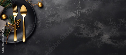 A banner with golden cutlery on a black stone table, representing a table setting for Christmas or New Year. It can be used as a card, menu template, or for any other purpose. has copy space and