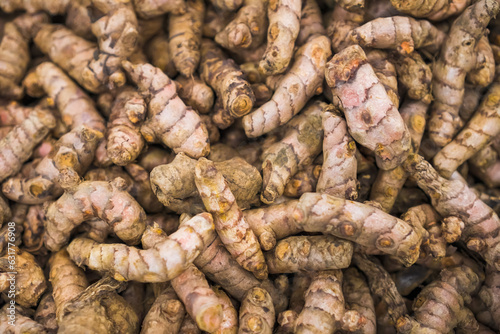 A lot of fresh turmeric root rhizome heap in market or groceries display. Concept for Herbal drinks, Alternative medicine, Organic Farming Harvest, Healthy food, relaxation ingredient. photo