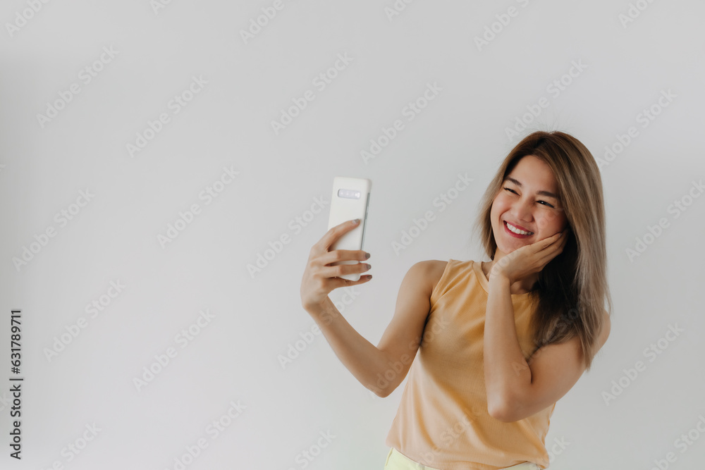 Asian Thai women taking selfie with happy smile in room with mobile phone, isolated white background. Asian Thai women taking selfie with happy smile in room with mobile phone, isolated white background.