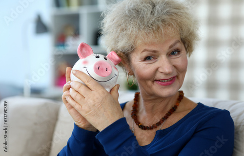 Cuadro en lienzo Portrait of cheerful aged grandmother with pink piggy bank