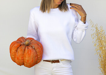 Girl in template blank white sweatshirt isolated on white background with halloween orange pumpkin.