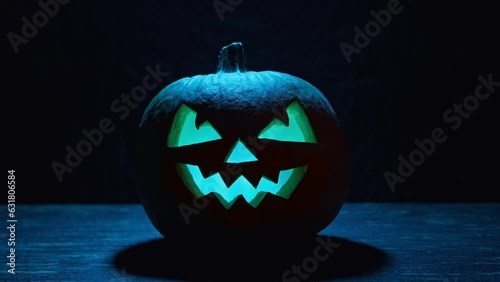 Halloween pumpkin with flashing in different colors eyes on dark background. Jack o' Lantern at night. Pumpkin with scary colorful face. Halloween concept. 4K, UHD