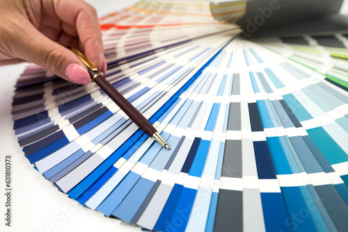 Person with a finger shows to the selected color in the palette for paint tinting. Colored catalog fan.