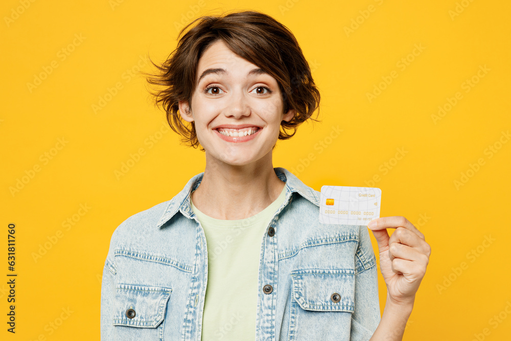 Young surprised shocked happy woman she wear green t-shirt denim shirt casual clothes look camera hold in hand mock up of credit bank card isolated on plain yellow background studio Lifestyle concept Young surprised shocked happy woman she wear green t-shirt denim shirt casual clothes look camera hold in hand mock up of credit bank card isolated on plain yellow background studio Lifestyle concept