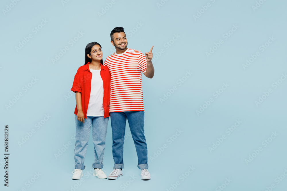 Full body young couple two friend family Indian man woman wear red casual clothes t-shirts together point index finger aside on area show something isolated on pastel plain blue cyan color background