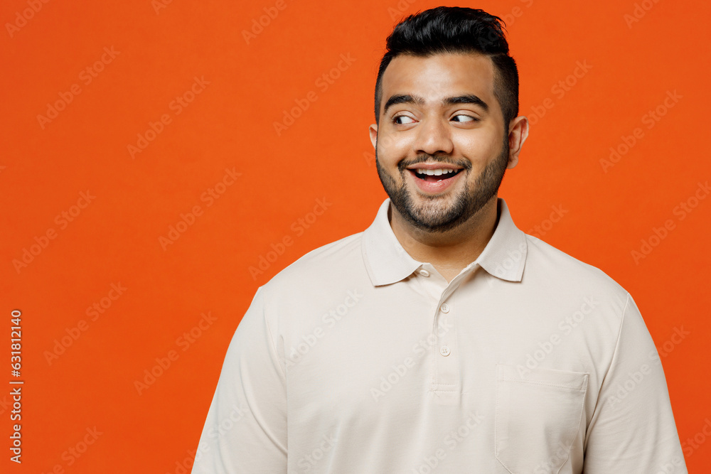 Young surprised shocked happy stunned impressed amazed Indian man he wearing white t-shirt casual clothes lok aside on area isolated on plain orange red background studio portrait. Lifestyle concept.