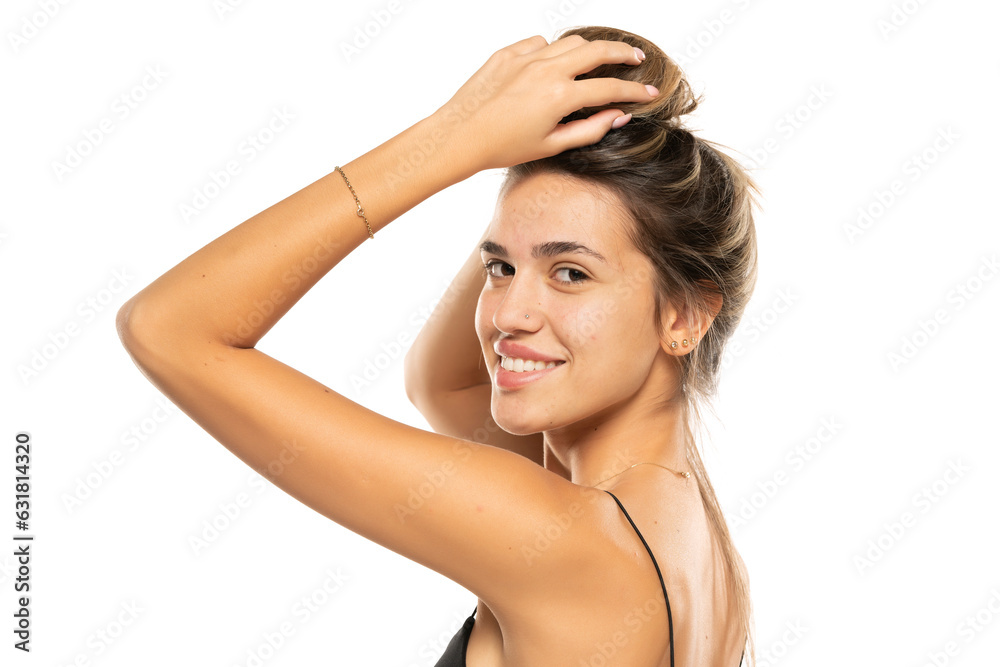 Young smiling beautiful woman tying her hair on a white studio background. Side view Young smiling beautiful woman tying her hair on a white studio background. Side view