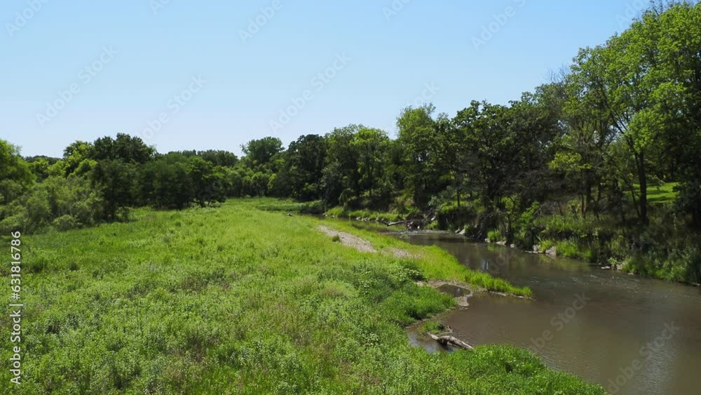 Small calm river alongside the green grass and green trees on a sunny day Small calm river alongside the green grass and green trees on a sunny day
