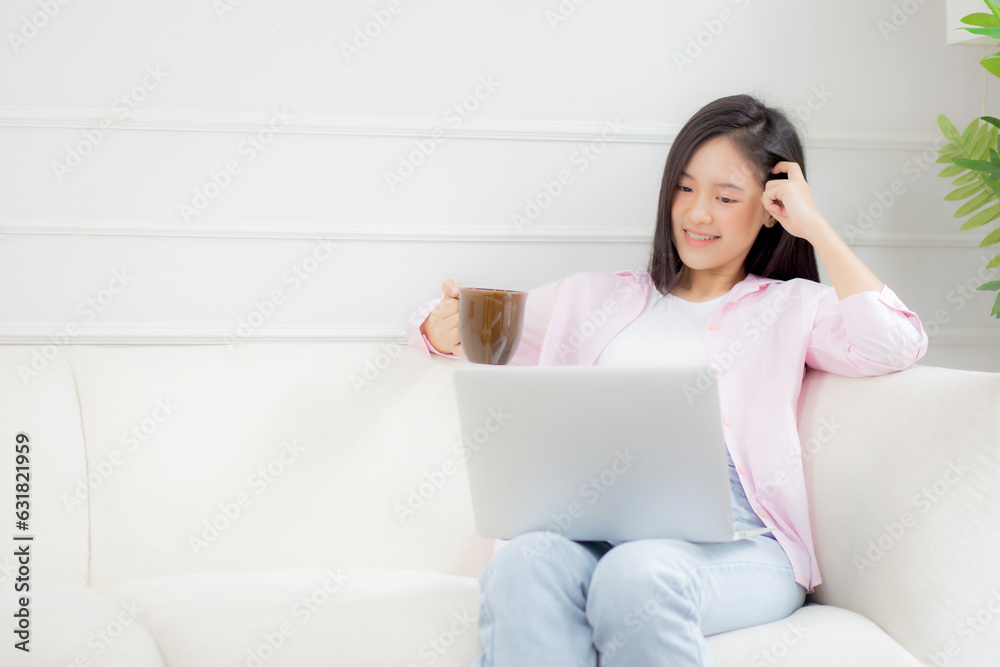 Young asian business woman work from home with laptop computer and drinking coffee on sofa in living room, freelance girl using notebook sitting on couch with comfort and relax, lifestyles concept. Young asian business woman work from home with laptop computer and drinking coffee on sofa in living room, freelance girl using notebook sitting on couch with comfort and relax, lifestyles concept.
