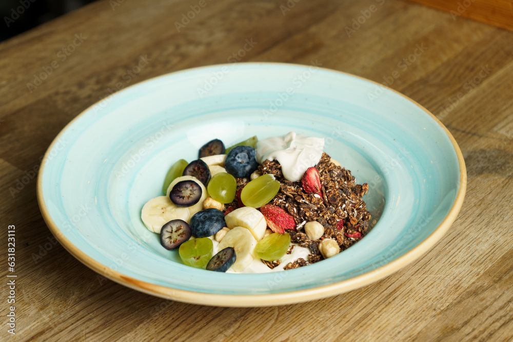 A bowl of cereal with fruits on a wooden table A bowl of cereal with fruits on a wooden table