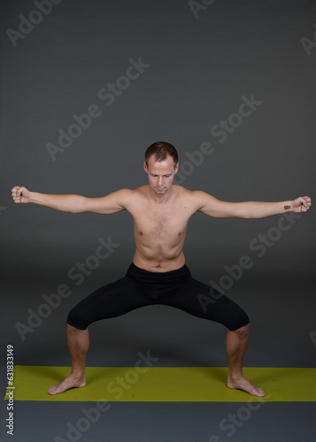 Man doing yoga in photo studio on isolated background. 