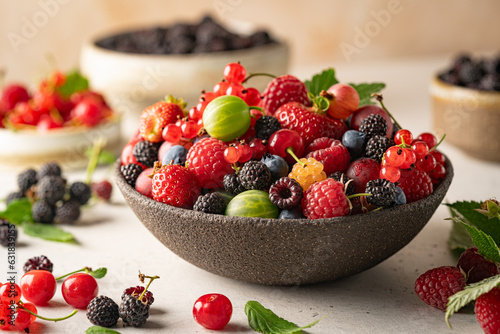 Various fresh berries in a bowl. Mix of different fresh berries on white background. Strawberries  raspberries  gooseberries and cherries are presented.