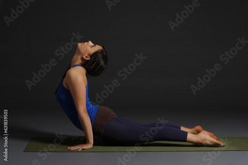 Woman doing yoga in photo studio on isolated grey background.