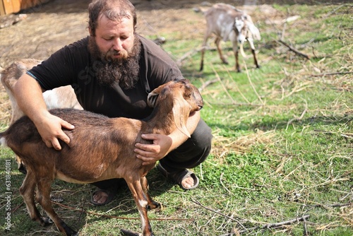 Bearded man hugging an Anglo-Nubian goat © Владимир Коврижник