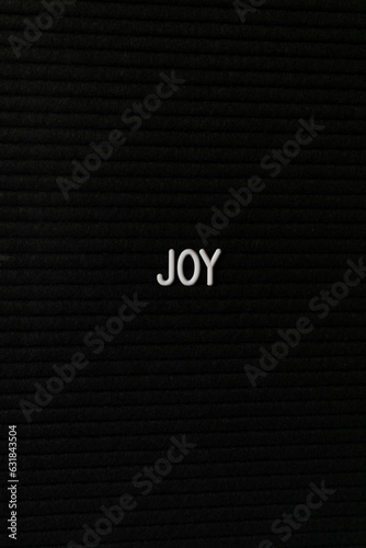 Vertical black spongy board with a text "joy" for background