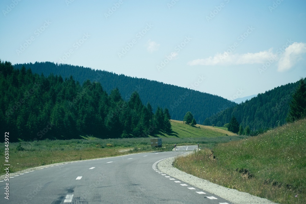 Beautiful view of an asphalt road through green hills under a blue sky.