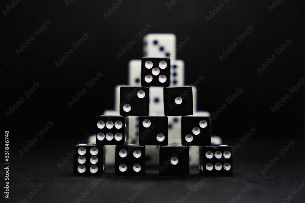 Close up of black and white dice stacked in the shape of a pyramid isolated on a black background Close up of black and white dice stacked in the shape of a pyramid isolated on a black background