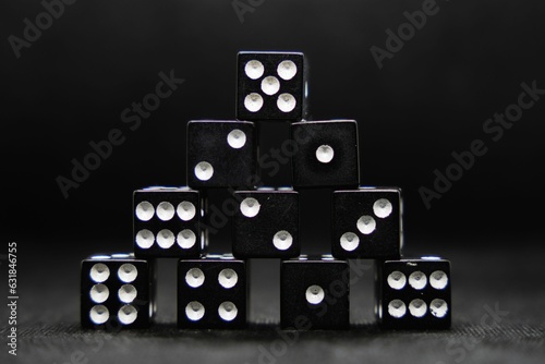 Close up of black dice stacked in the shape of a pyramid isolated on a black background