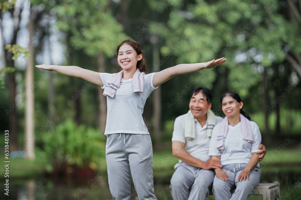 Asian daughter exercising in public beauty, happily encouraged by her parents in the background.