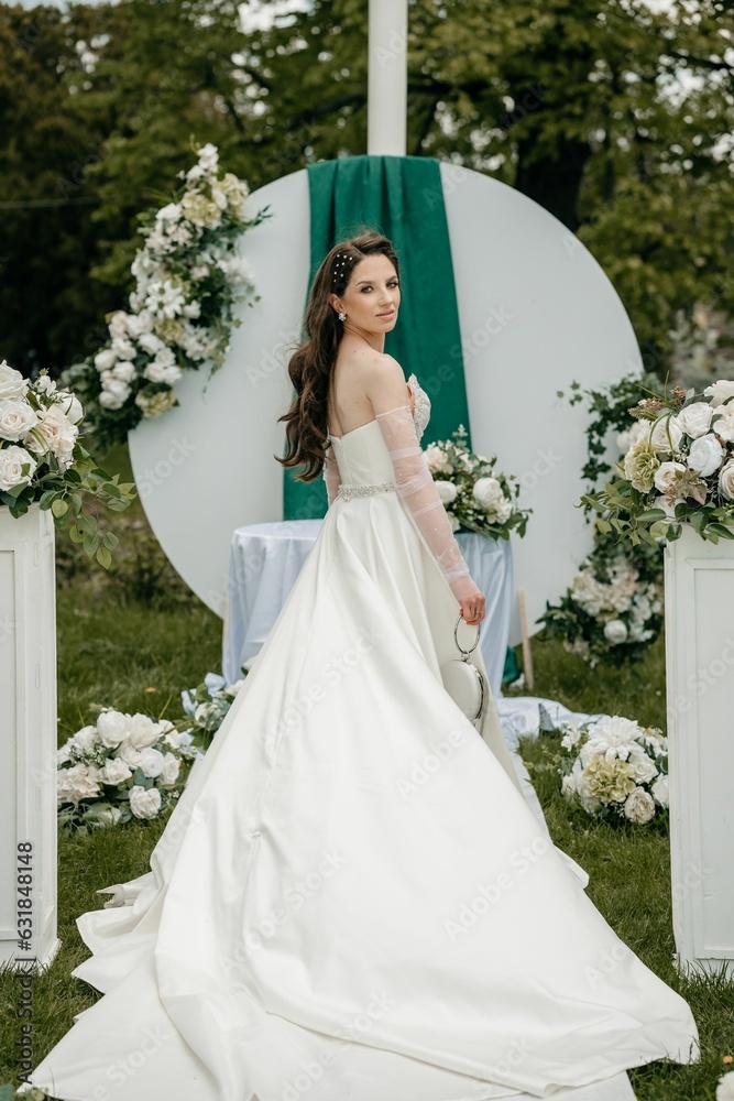 Beautiful bride posing in her wedding dress in a green park Beautiful bride posing in her wedding dress in a green park