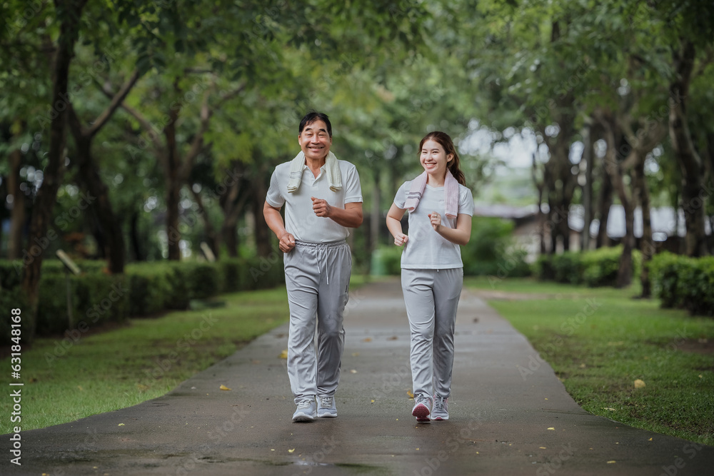 Young beautiful asian woman jogging with her father in park happily, with a smile. Asian woman jogging with her father for health care, park exercise, health care. concept health care life insurance. Young beautiful asian woman jogging with her father in park happily, with a smile. Asian woman jogging with her father for health care, park exercise, health care. concept health care life insurance.