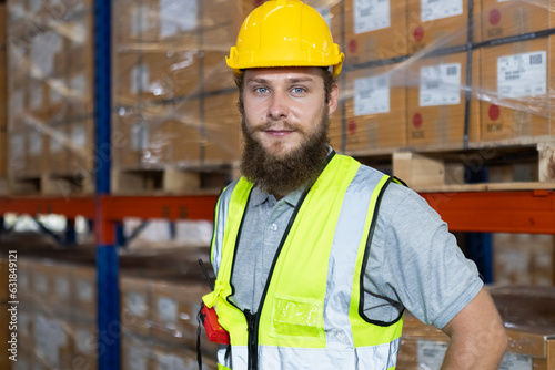 portrait of man have a beard face wearing safety uniform looking at camera standing in warehouse factory. Male professional worker check stock inspecting goods on shelves in warehouse.
