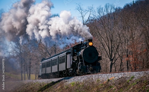 Photo A steam passenger train moving slowly blowing lots of black smoke and white steam on a sunny day