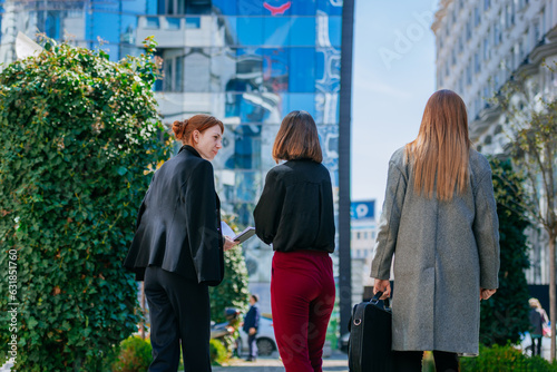 Back view shot of ginger  brunette and blonde businesswomen walking and having a conversation
