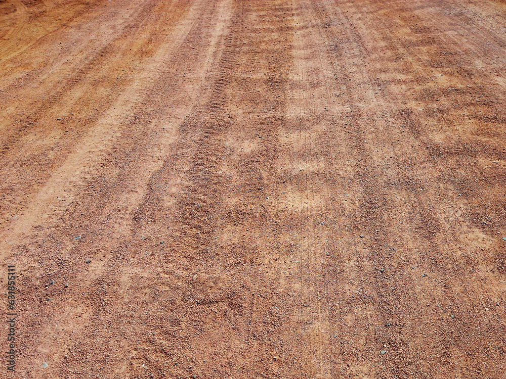 Unpaved road texture. Rough background of vehicle tracks on wet sand. Rough sandstone road background.