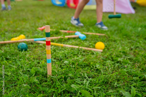 Children croquet game wooden mallets and balls on green grass at garden party photo