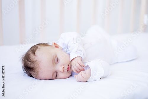 baby girl sleeping on a bed on a white cotton bed, sweet sleep cute newborn baby baby at home in a crib close-up