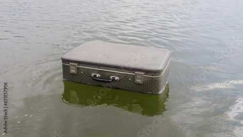 vintage suitcase sails along the waves of natural  body of water