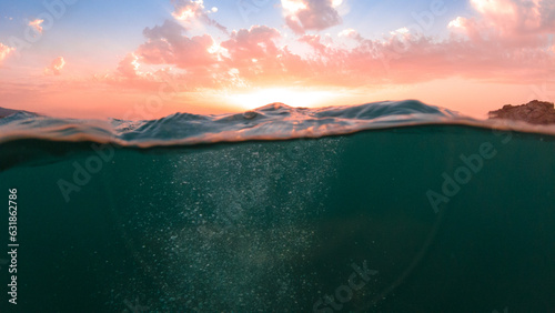 Underwater part and sunset skylight splitted by waterline, underwater bubbles. Beautiful clouds and bright sun over sea water, Real image very suitable for backgrounds in Mediterranean sea, undersea.