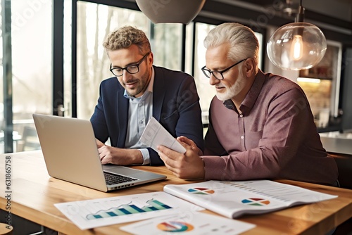 Mature male businessman and his senior father looking at and studying monthly finances on laptop computer