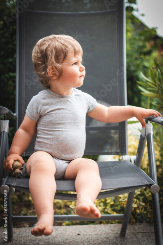 Baby im Sommer auf Gartenstuhl mit Spielfigur