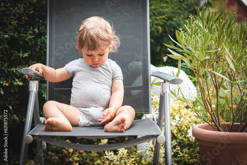 Baby im Sommer sitzt auf Gartenstuhl