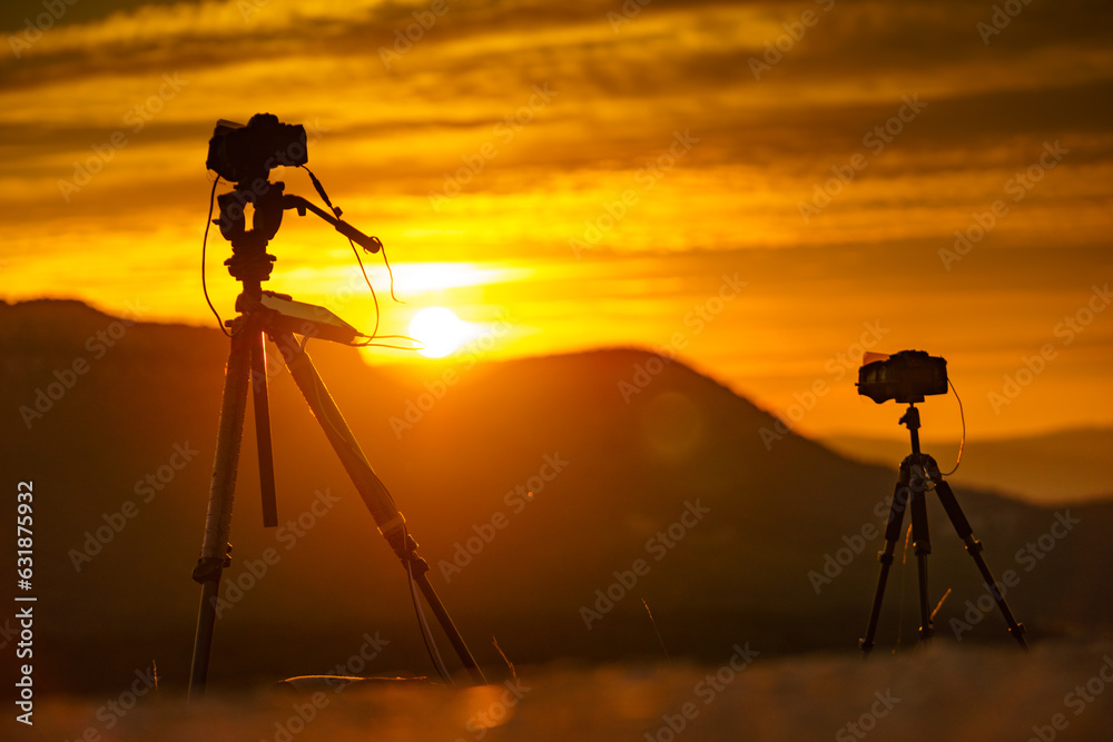 Camera on tripod take photo from sunrise over mountain