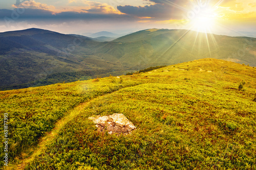 narrow path through grassy meadow on top of the hill in high mountain at sunset. beautiful countryside scenery in evening light