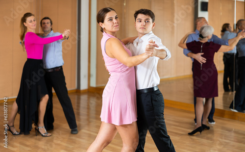 Active young pair practicing ballroom dance in training hall during dancing-classes. Pairs training ballroom dance