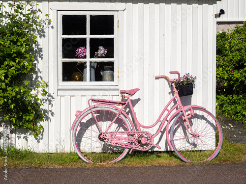 Vrango, Sweden - May 31, 2023: A pink bicycle leaning against a white wooden Swedish house