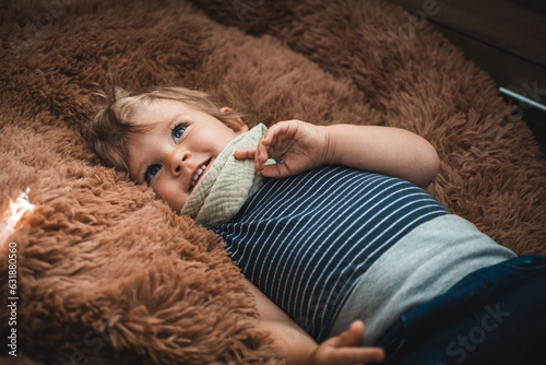 Kind liegt in braunem Kuschelkissen und lächelt