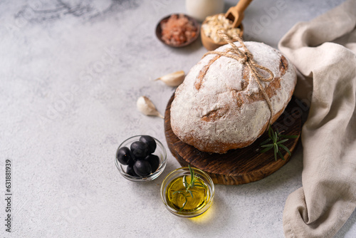 Fresh organic homemade artisan ciabatta bread with herbs, olive oil and olives on white rustic background. sourdough bread